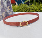 Tan leather belt with gold-tone circular buckle and adjustable holes