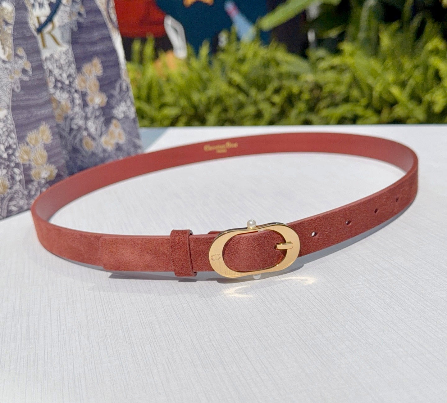Tan leather belt with gold-tone circular buckle and adjustable holes