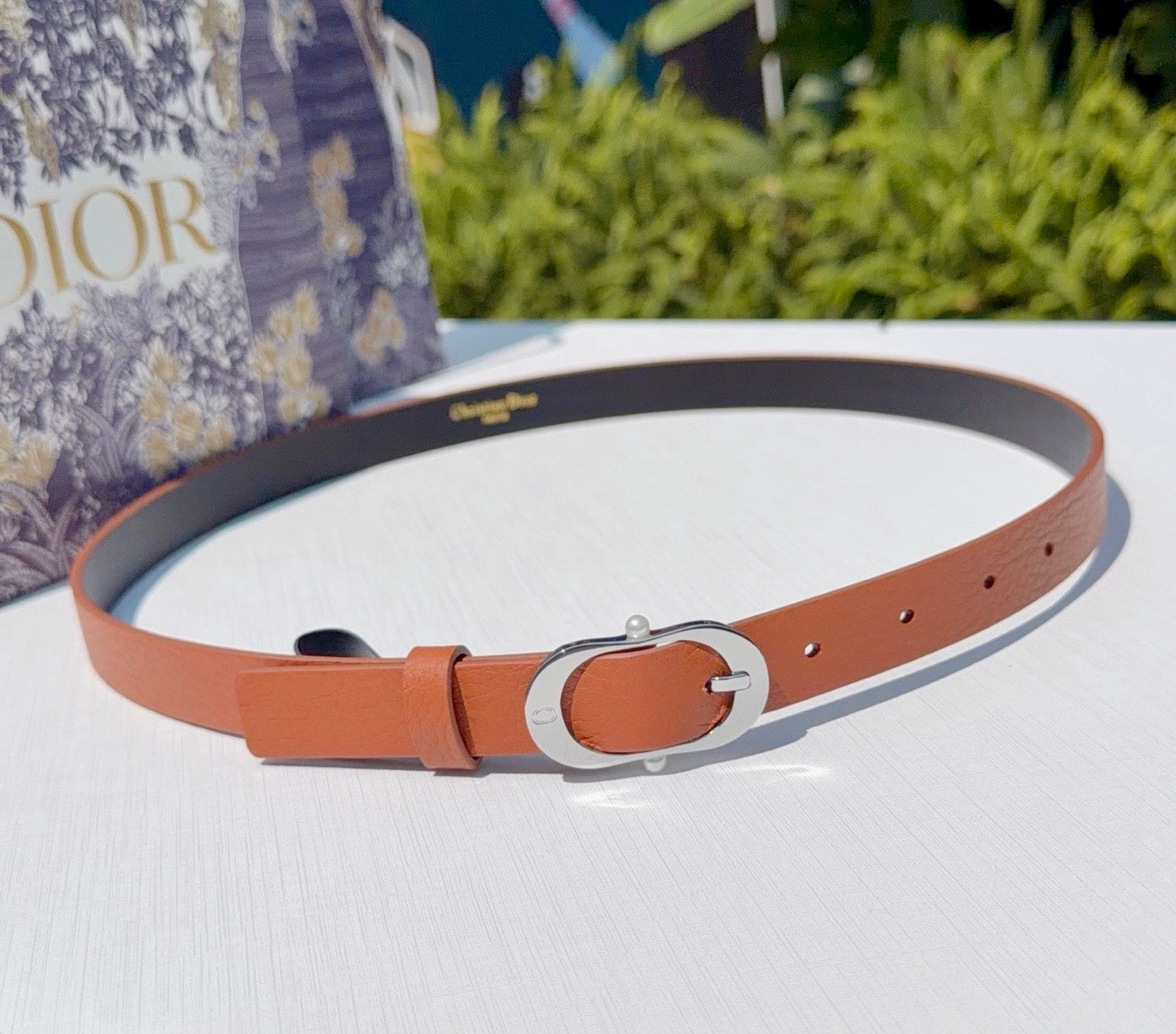 Dior leather belt with orange strap, silver-toned oval buckle, and punched holes