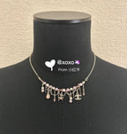 Gold-tone charm necklace with pink bead dangles, heart and star pendants on stand