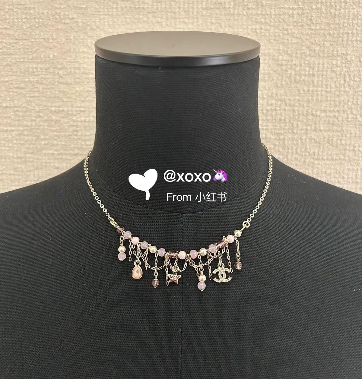 Gold-tone charm necklace with pink bead dangles, heart and star pendants on stand