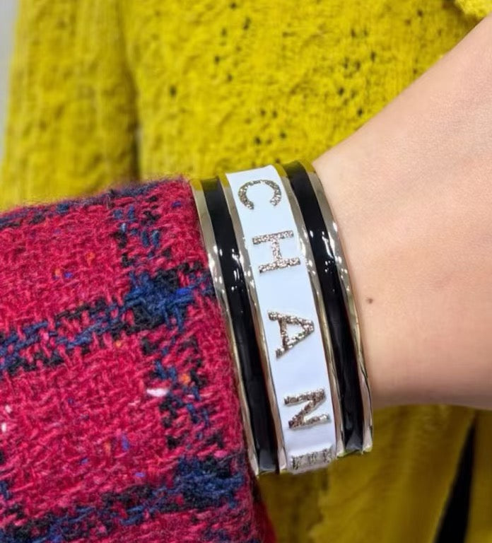Black cuff bracelet with white CHANEL letters on a wrist