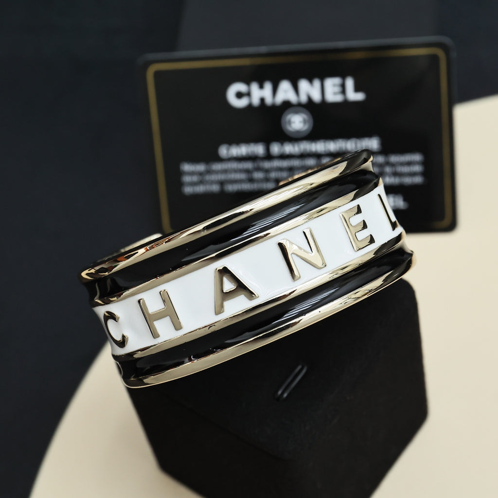 Gold-tone cuff bracelet with white CHANEL lettering on the stacked bands