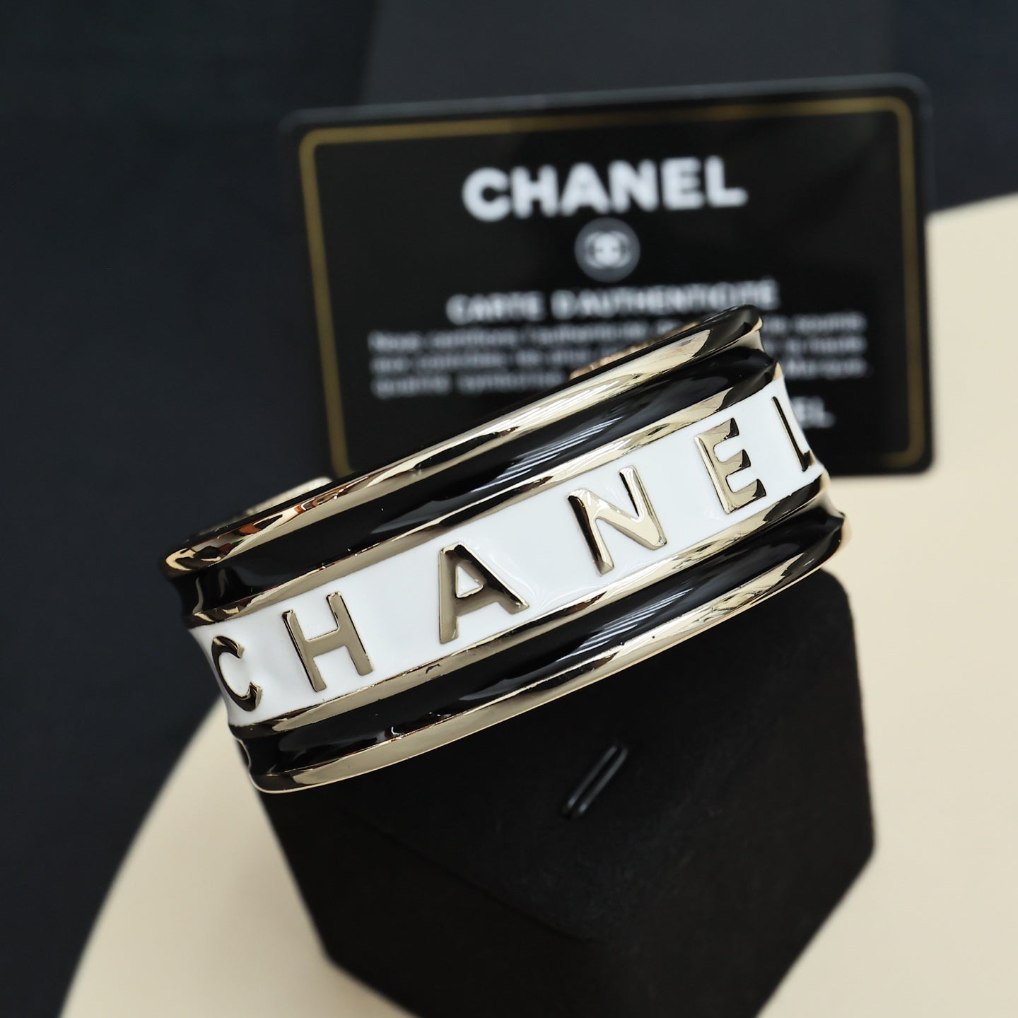 Gold-tone cuff bracelet with white CHANEL lettering on the stacked bands