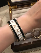 Black-and-silver cuff bracelet with white CHANEL letters on wrist