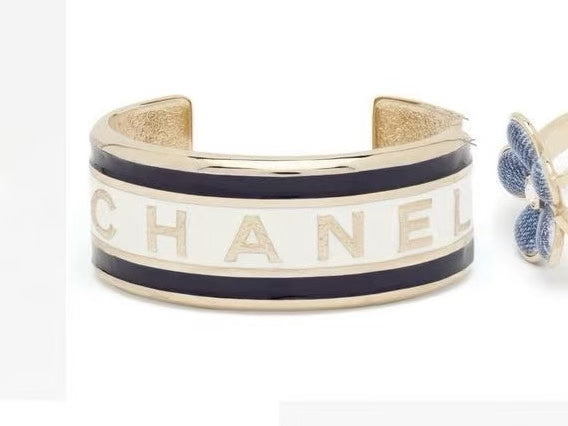 Navy-and-gold cuff bracelet with CHANEL letters on a white enamel band