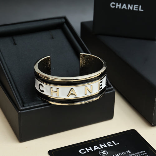 Gold-tone cuff bracelet with CHANEL lettering and black inset details