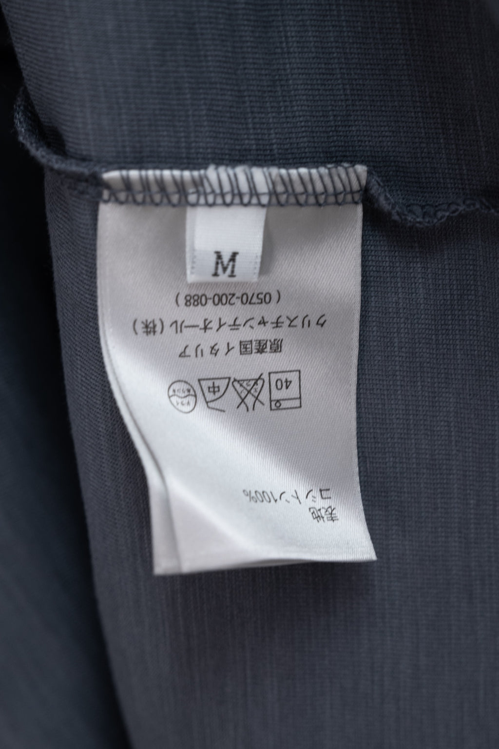 Dark blue T-shirt size M label and care symbols on inner tag