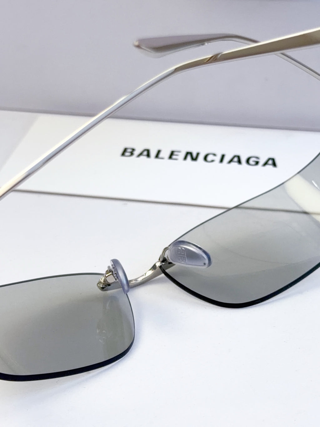 Balenciaga sunglasses with gold metal arms and gray tinted lenses, close-up of lens