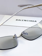 Balenciaga sunglasses with gold metal arms and gray tinted lenses, close-up of lens
