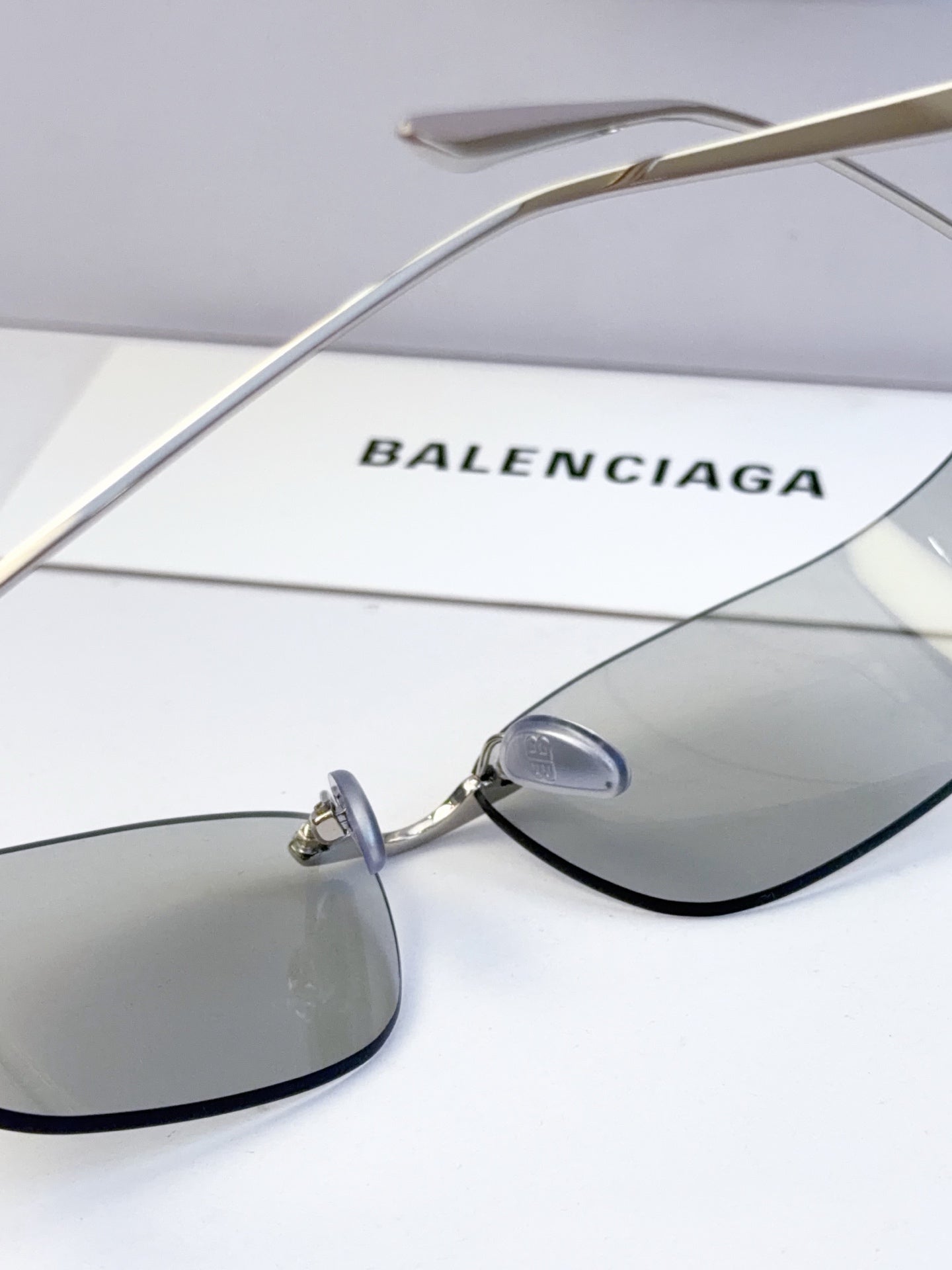 Balenciaga sunglasses with gold metal arms and gray tinted lenses, close-up of lens