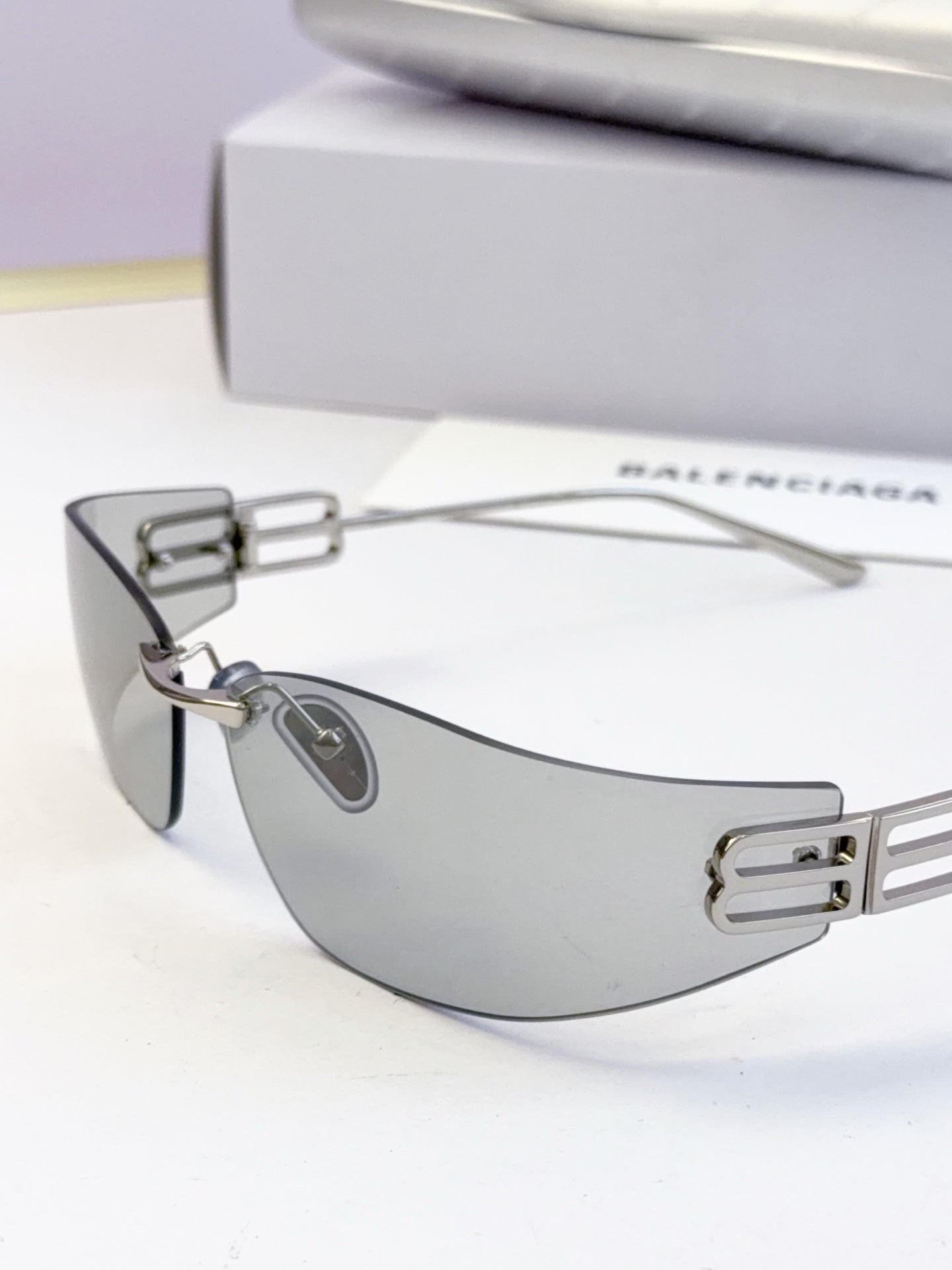 Balenciaga sunglasses with dark lenses and silver-gray frame, visible logo bar detail