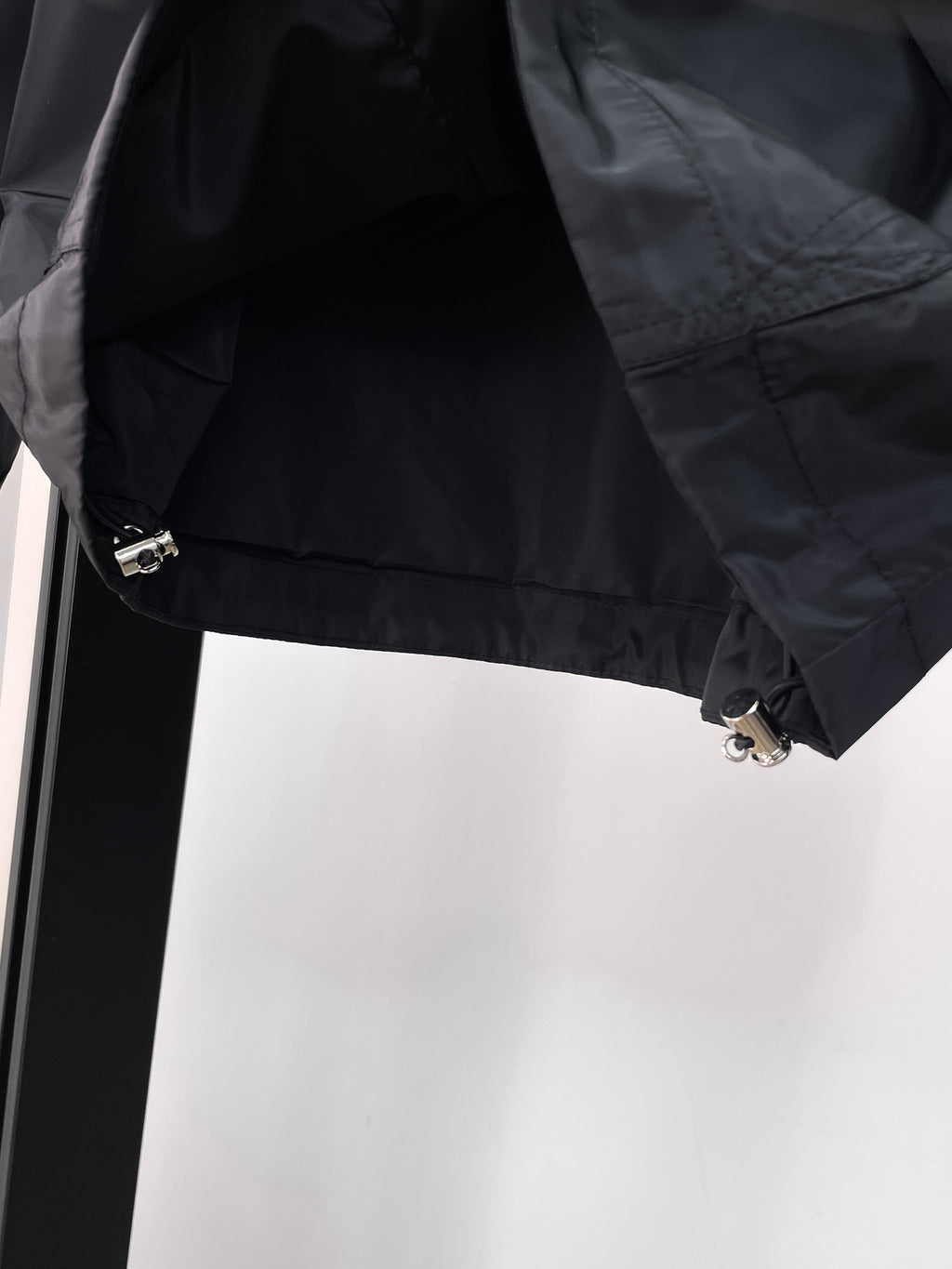 Long jacket lower sleeve detail in dark gray with snap and metal zipper hardware