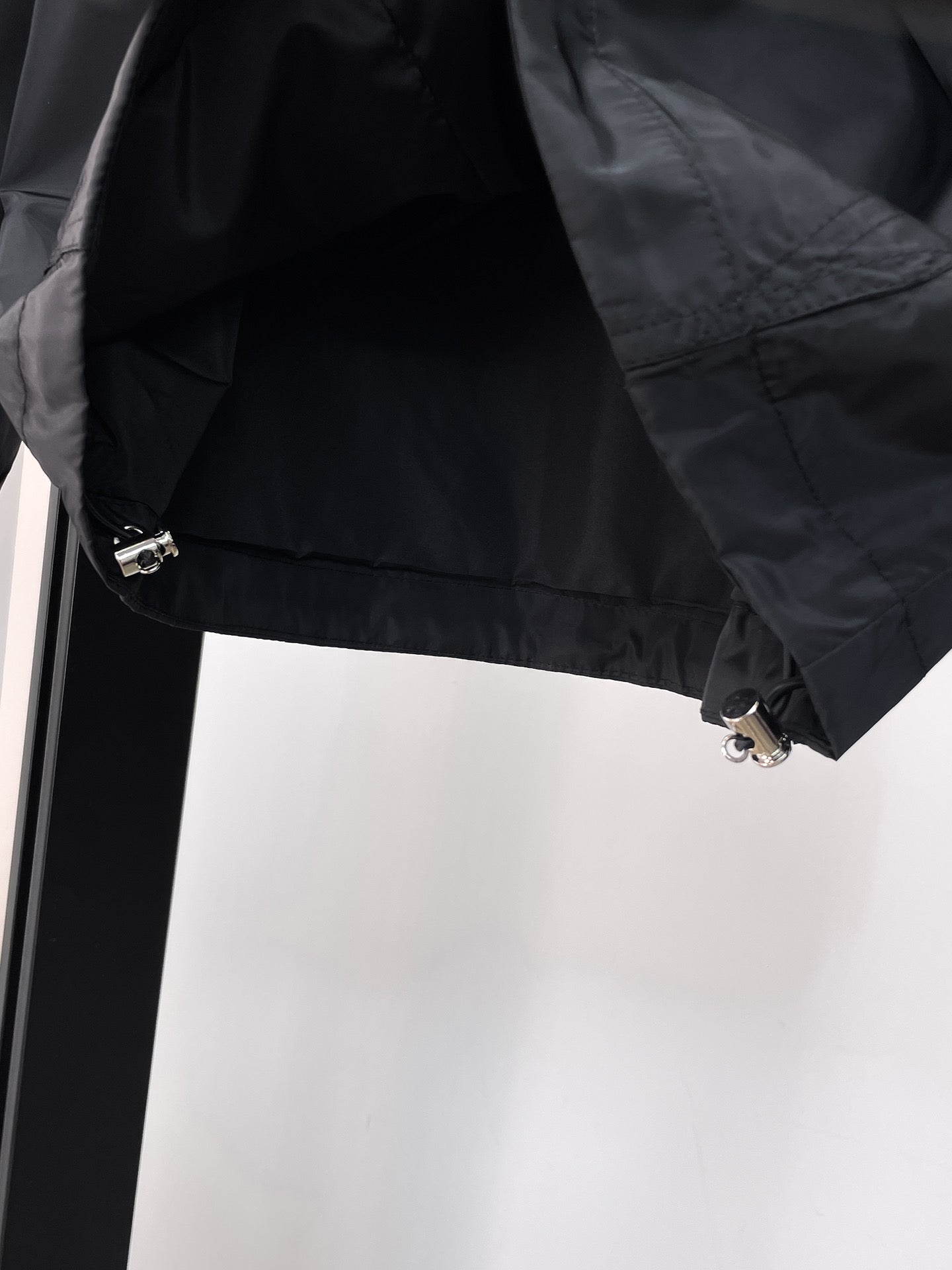 Long jacket lower sleeve detail in dark gray with snap and metal zipper hardware