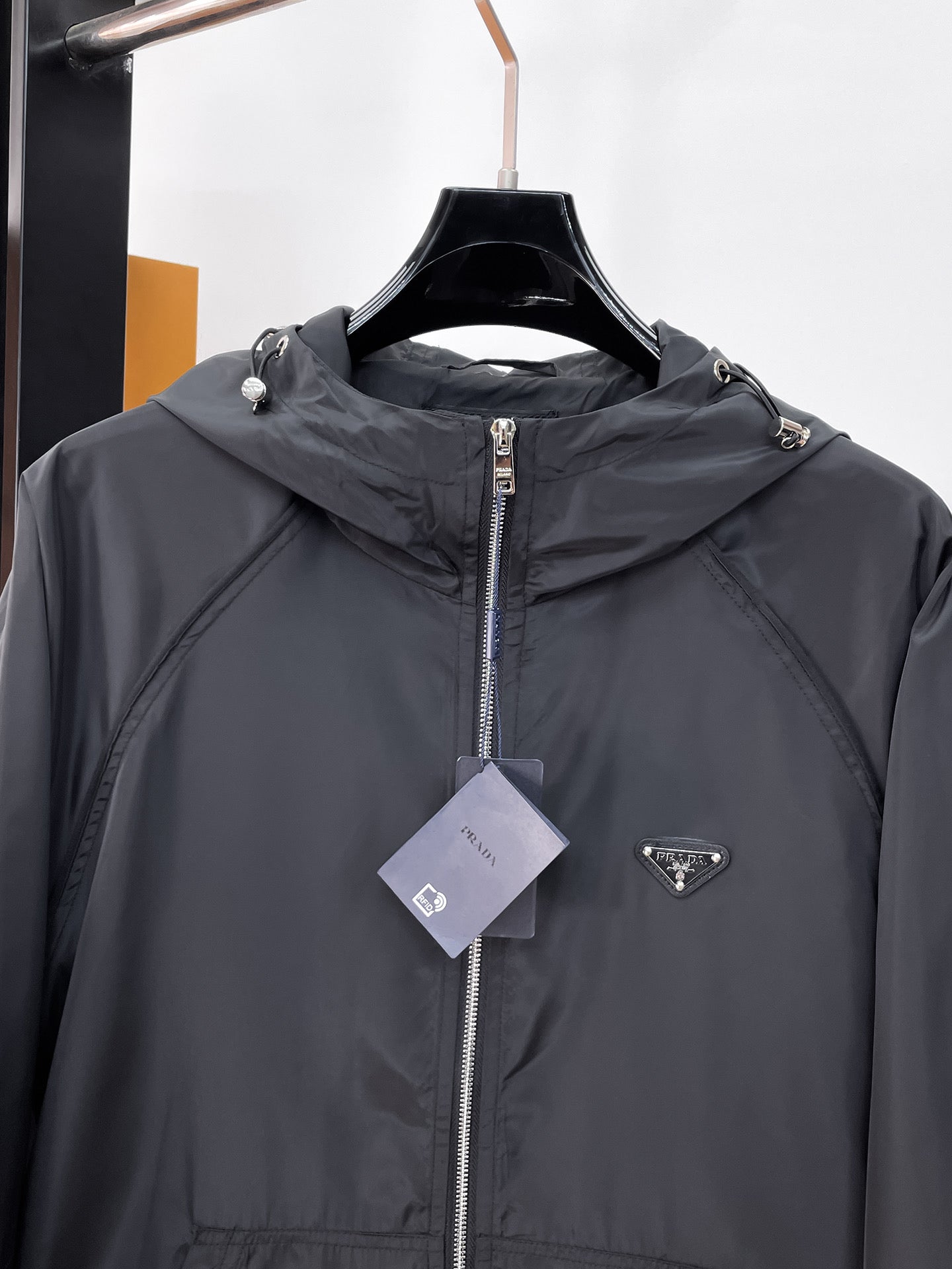 Long hooded zip jacket chest detail in dark gray with center zipper and logo patch