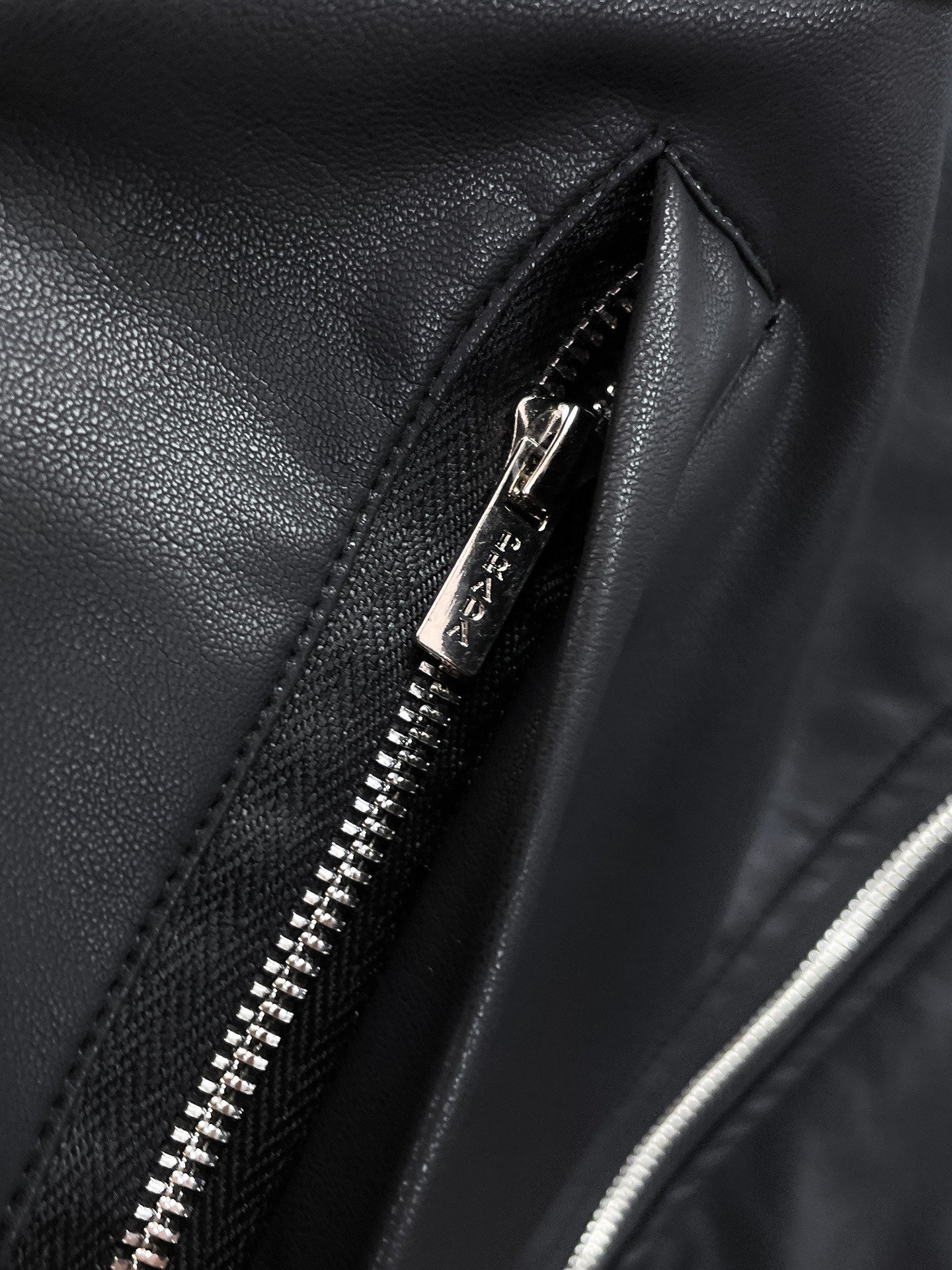 Black jacket close-up: front zipper with metal teeth on textured fabric