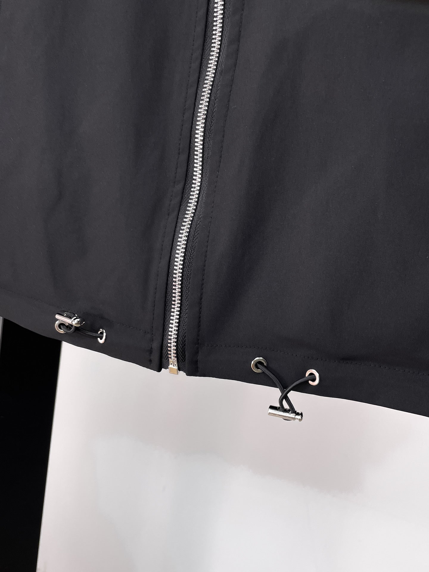 Black long jacket front with silver zipper and eyelet drawstring hem