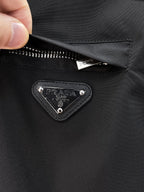 Prada triangle logo patch on dark jacket with silver rivets and top stitch