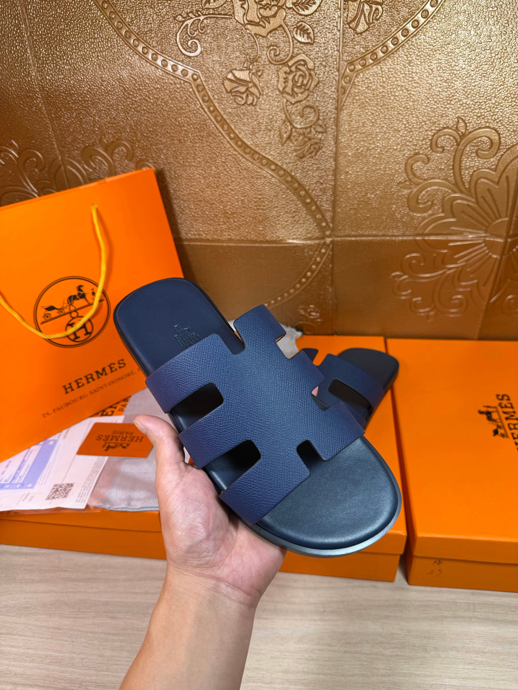 Hand holding dark blue slide sandal with wide strap bands and open toe