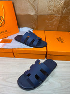 Pair of dark blue slide sandals with wide cross straps and cutout sections