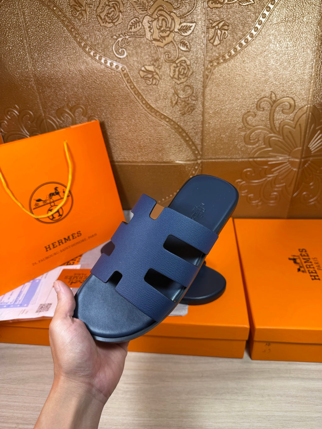Hand holding dark blue slide sandals with thick bands and cutout detailing