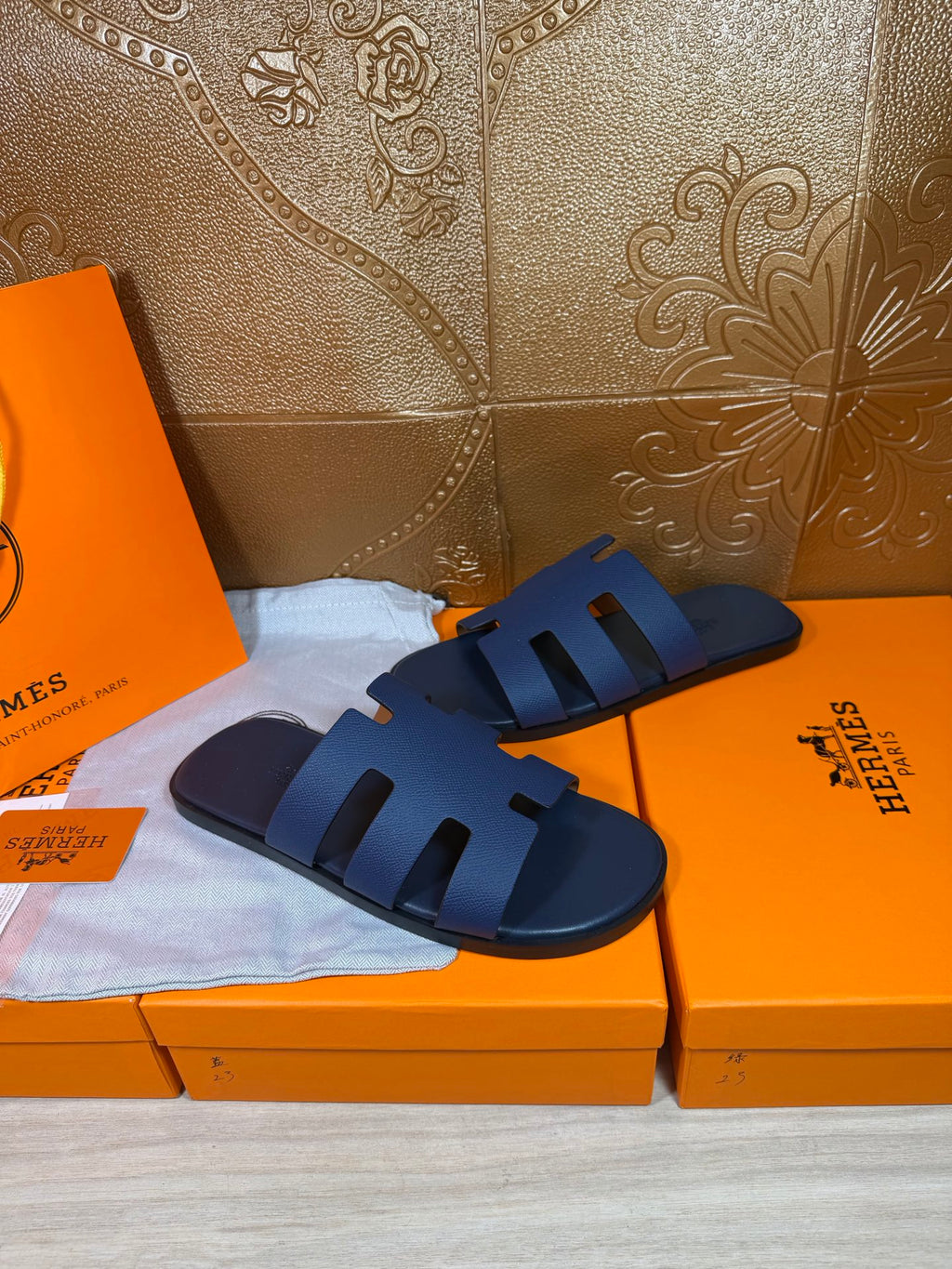Dark blue slide sandals resting on orange shoe boxes, open toe