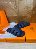 Dark blue slide sandals resting on orange shoe boxes, open toe