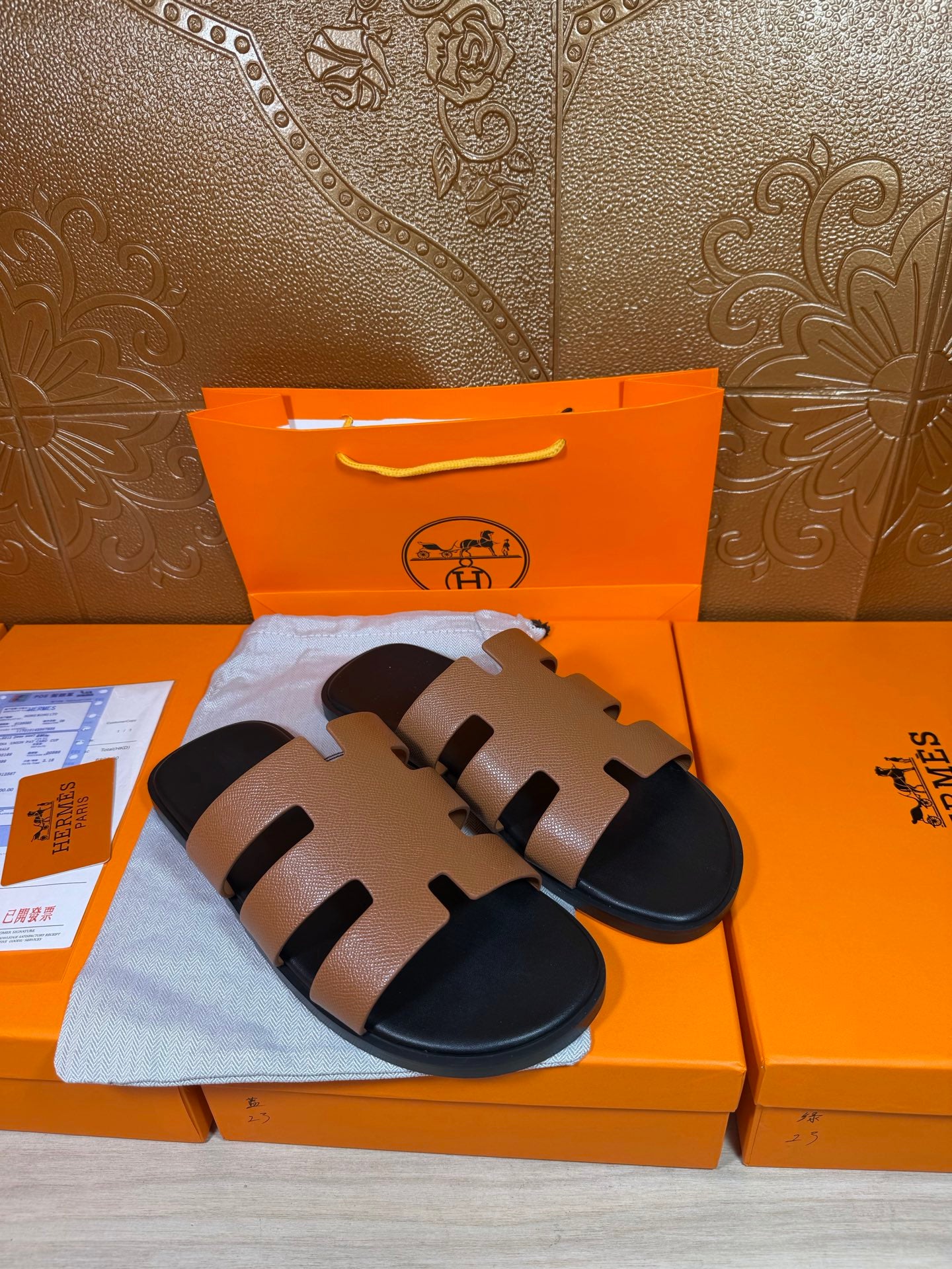 Pair of brown-and-black slide sandals with wide band straps over dark soles