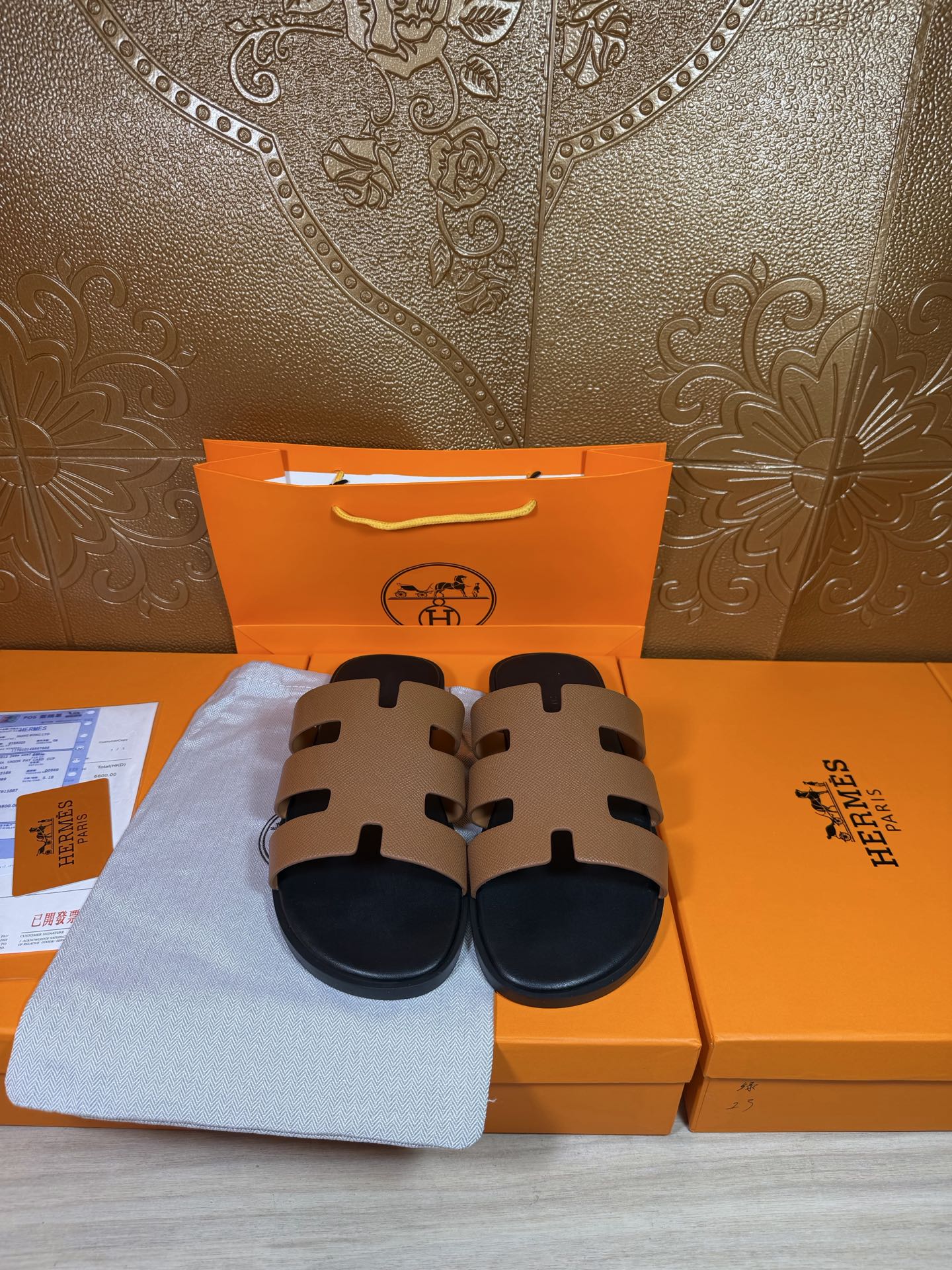 Brown and black slide sandals on display with wide strap bands and dark soles