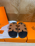 Brown and black slide sandals with wide strap cutouts and dark footbeds
