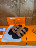 Brown leather slide sandals with wide strap bands and dark molded footbeds