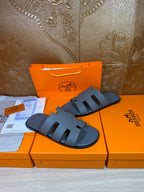 Two Hermes slide sandals in dark blue with wide cutout straps and open toe