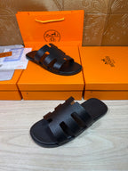 Black slide sandals with wide crisscross straps and open toe, side angle