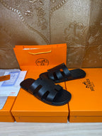Black slide sandals with wide band straps across the top and open toe