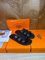 Black open-toe slide sandals with three wide straps and adjustable buckle tabs