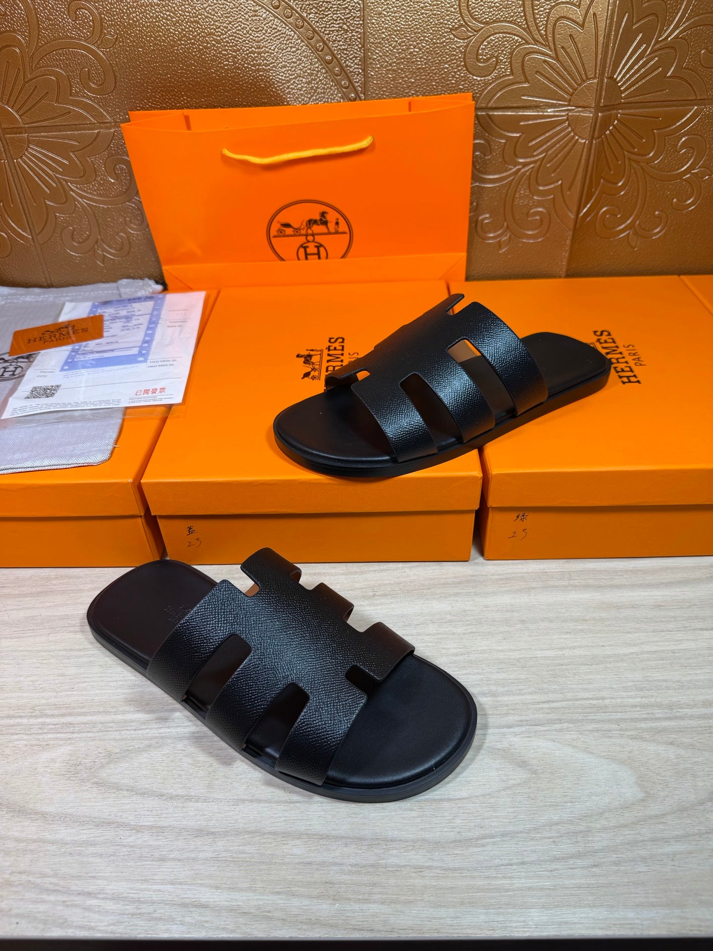 Black slide sandals with wide straps and buckle-like accents, open toe view