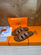 Pair of brown slide sandals with three wide cutout straps and smooth molded footbed.