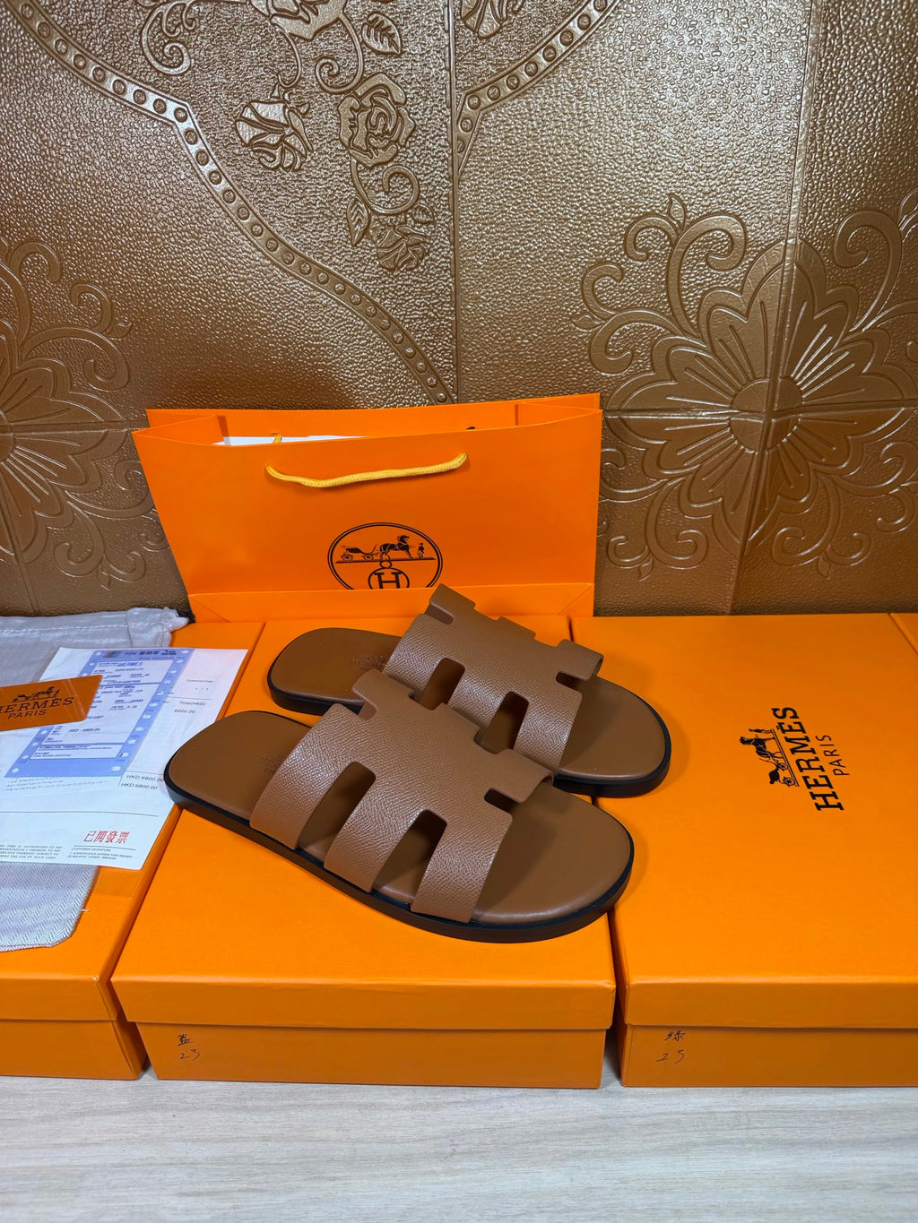 Brown slide sandals with wide, rectangular cutout straps and dark outsole details.