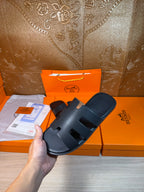 Hermes slide sandals held up, dark navy wide straps and textured footbed