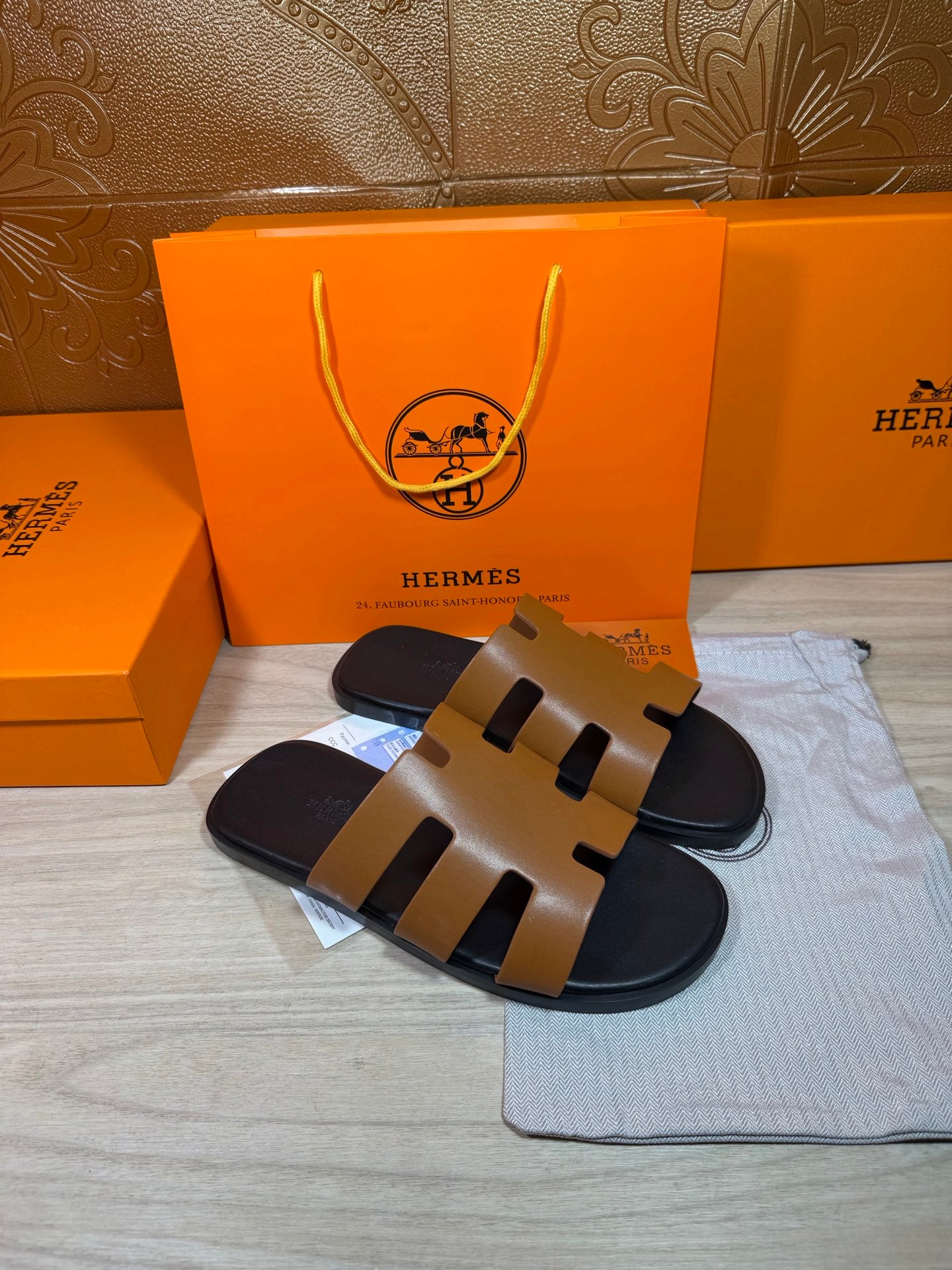 Hermes slide sandals with tan cutout straps and black sole, side view.