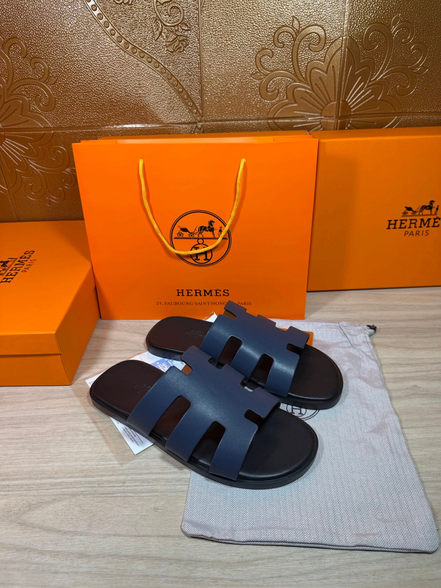 Hermes open-toe slide sandals, dark blue leather with three wide strap panels, front view.