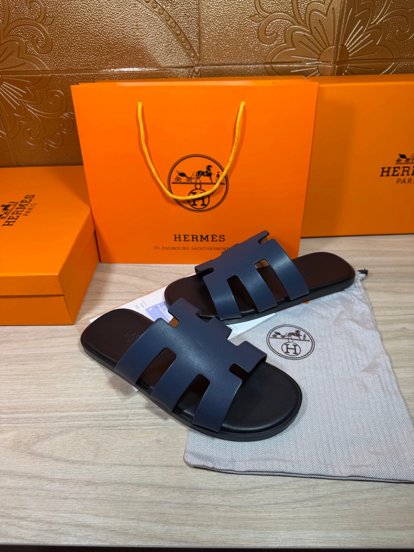Hermes open-toe slide sandals, dark blue leather with three wide straps and H logo sole.