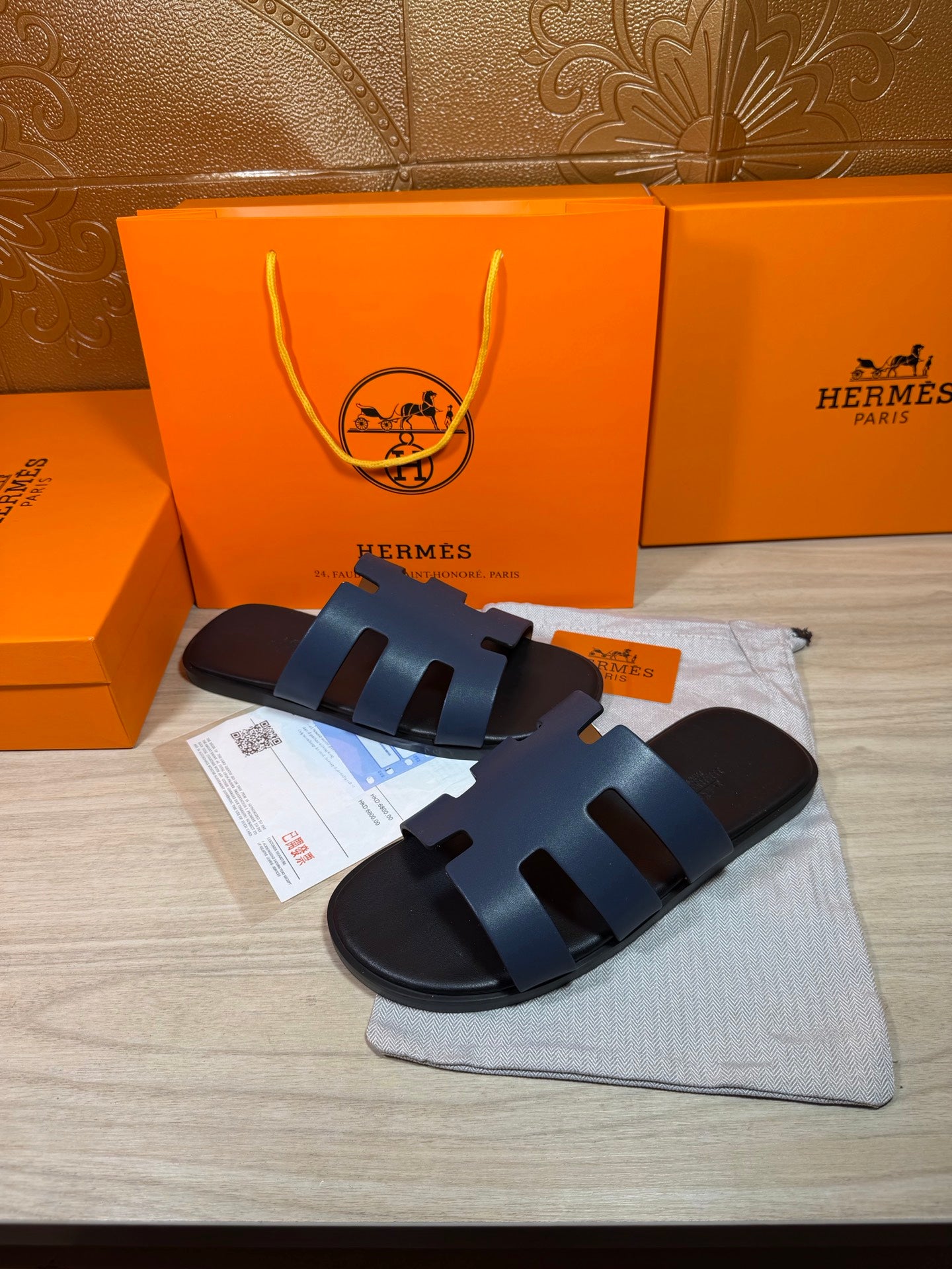 Hermes open-toe slide sandals, dark blue leather with three wide strap panels and H logo sole.