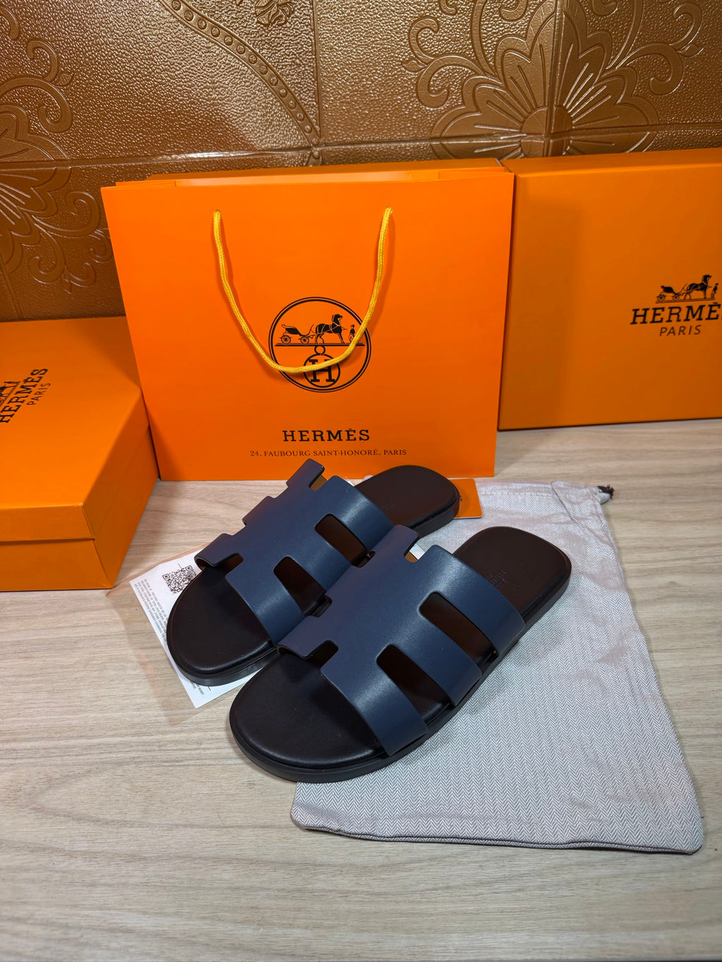 Hermes open-toe slide sandals, dark blue leather with three wide strap panels, side view.