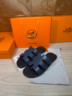 Hermes open-toe slide sandals, dark blue leather with three wide strap panels, side view.