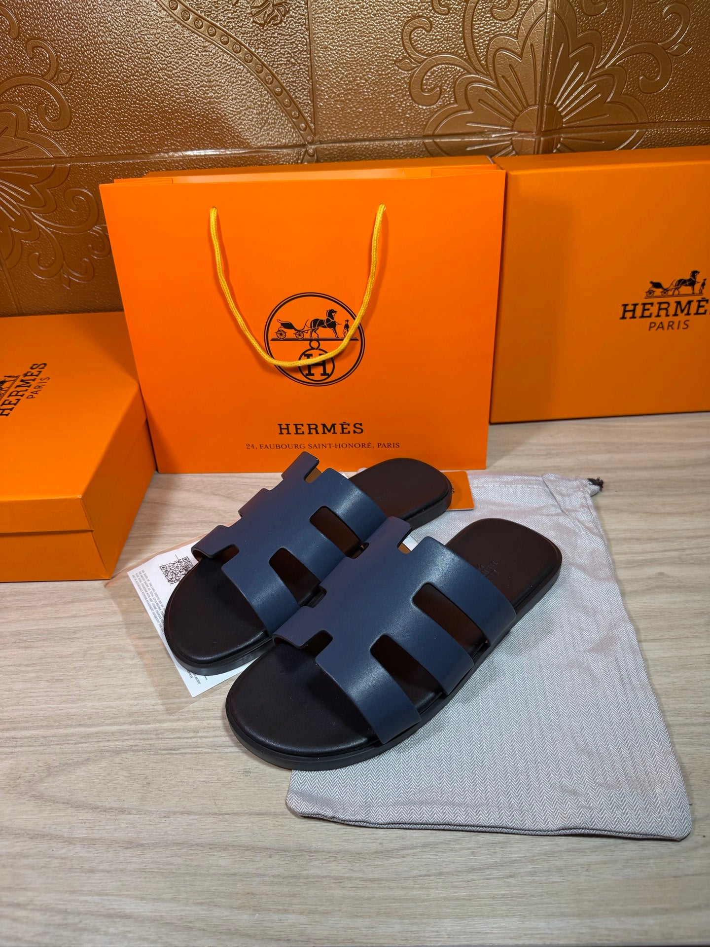 Hermes open-toe slide sandals, dark blue leather with three wide strap panels, side view.
