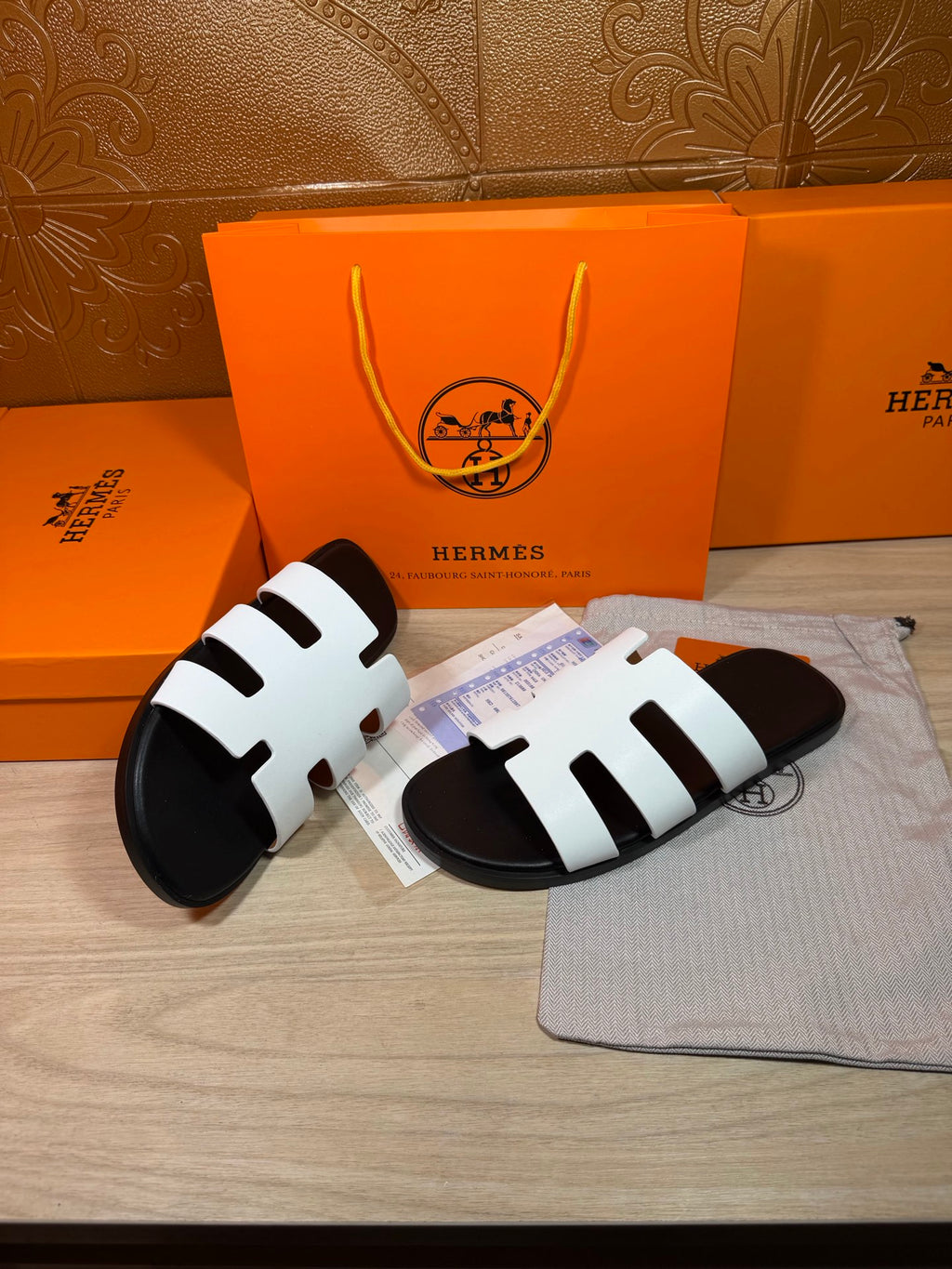 Hermes sandals with white straps and black footbeds, angled on cloth