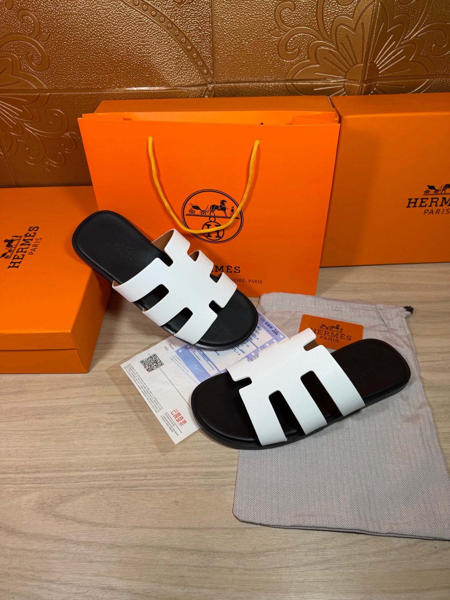 Hermes slide sandals with white straps and black footbeds, pair on garment bag