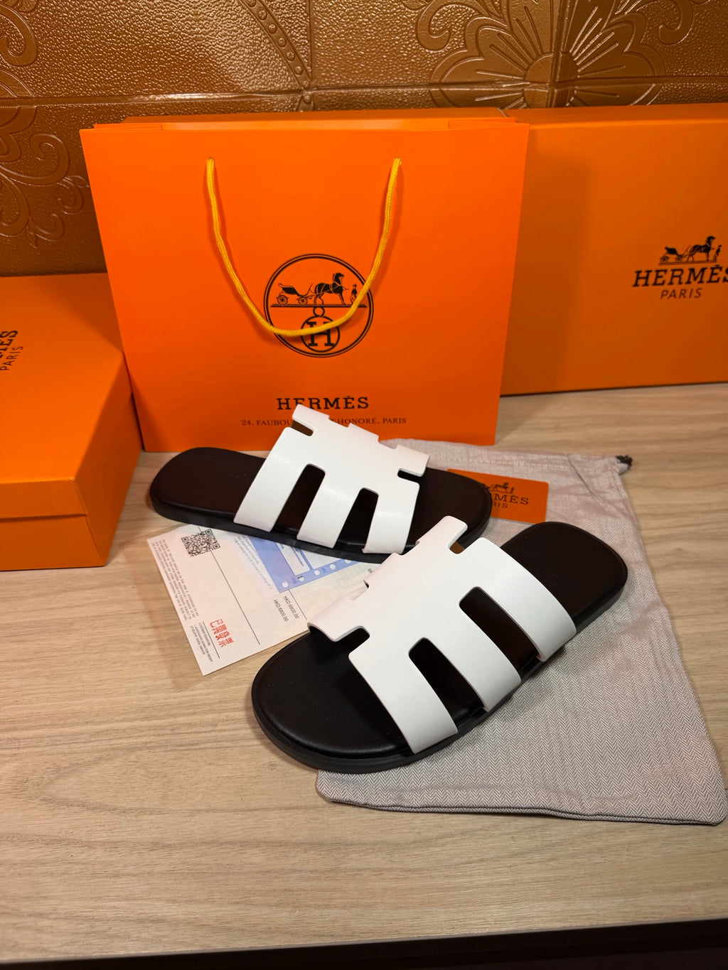 Hermes slide sandals with white straps and black footbeds, with purchase tags
