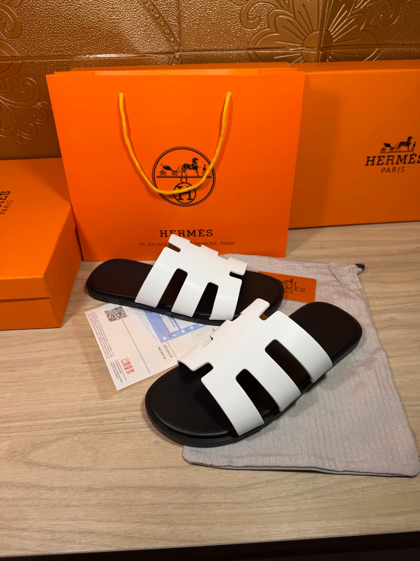 Hermes slide sandals with white straps and black footbeds, with purchase tags